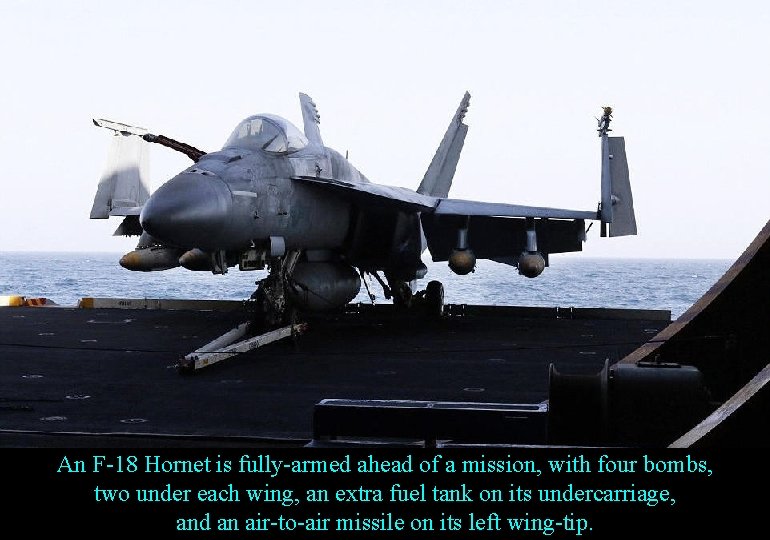 An F-18 Hornet is fully-armed ahead of a mission, with four bombs, two under