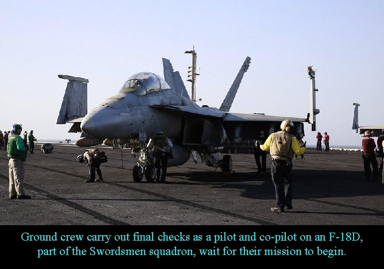 Ground crew carry out final checks as a pilot and co-pilot on an F-18