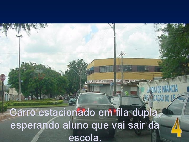 Carro estacionado em fila dupla, esperando aluno que vai sair da escola. 