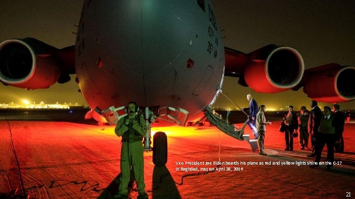 Vice President Joe Biden boards his plane as red and yellow lights shine on