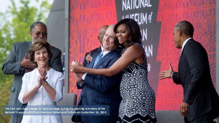 The First Lady hugs George W. Bush on stage during the opening ceremony of