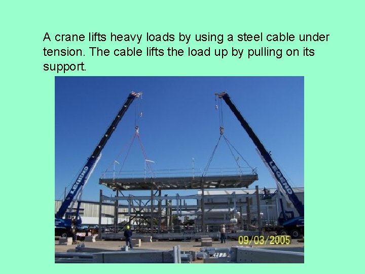 A crane lifts heavy loads by using a steel cable under tension. The cable