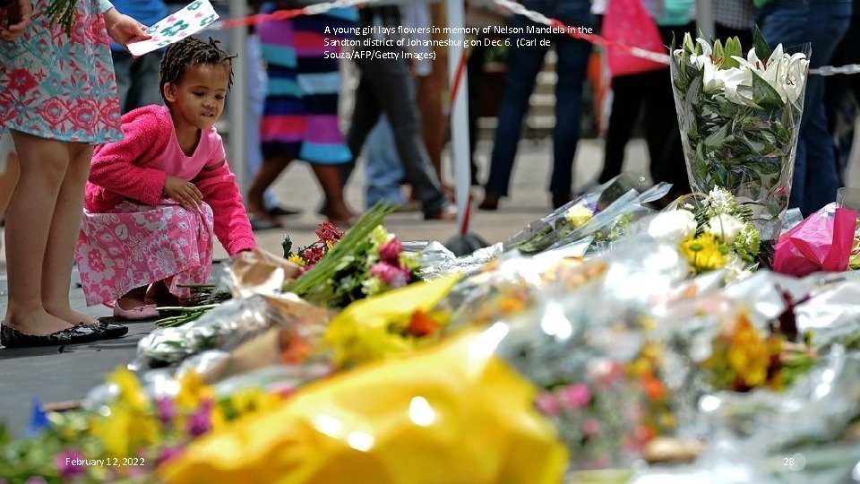 A young girl lays flowers in memory of Nelson Mandela in the Sandton district