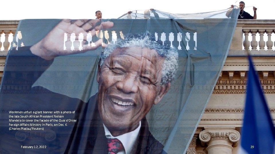 Workmen unfurl a giant banner with a photo of the late South African President