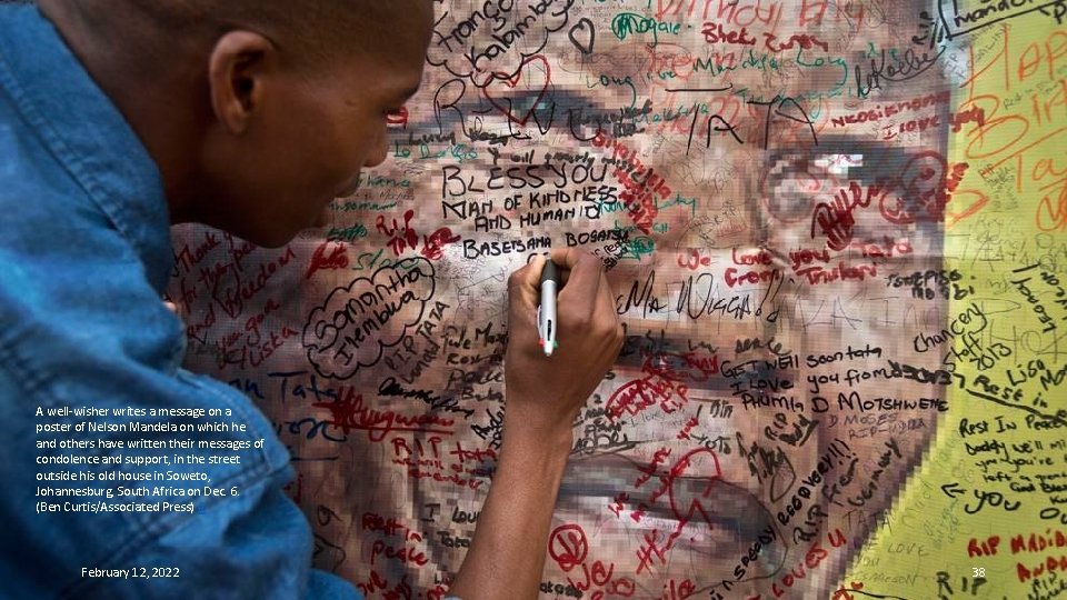 A well-wisher writes a message on a poster of Nelson Mandela on which he