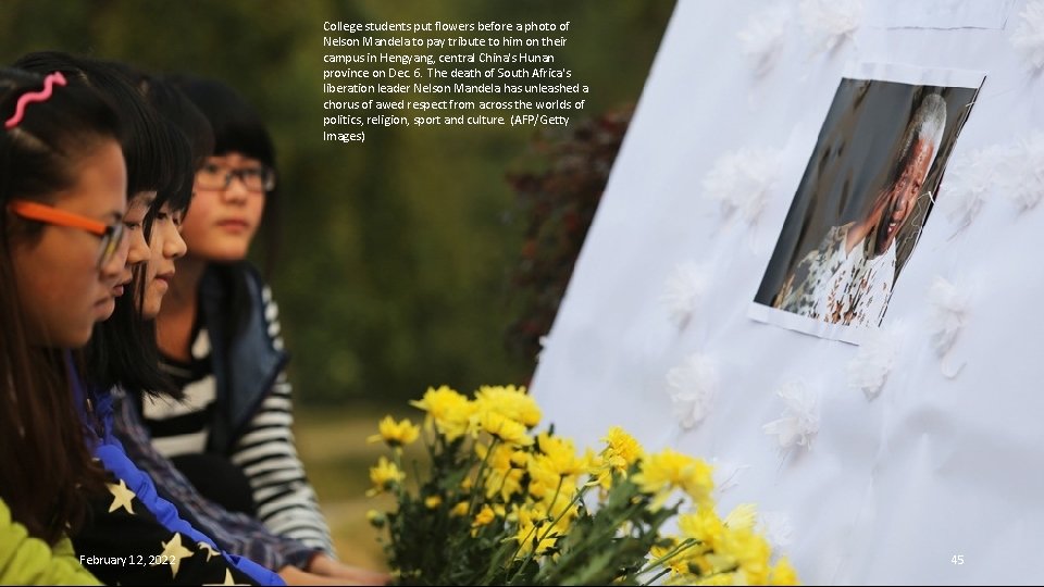 College students put flowers before a photo of Nelson Mandela to pay tribute to