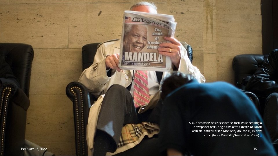 A businessman has his shoes shined while reading a newspaper featuring news of the