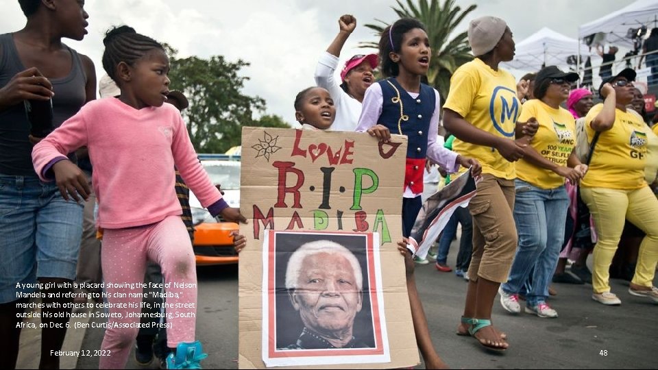 A young girl with a placard showing the face of Nelson Mandela and referring