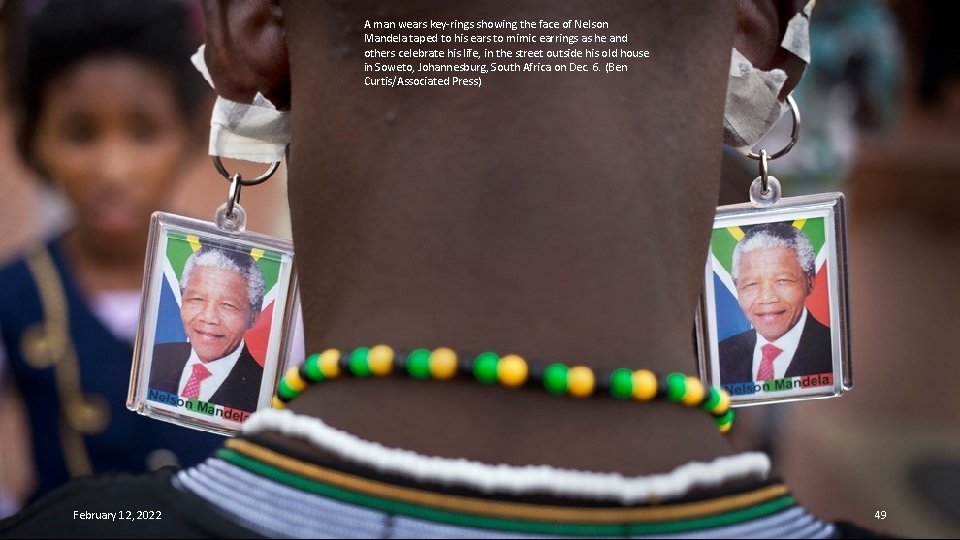 A man wears key-rings showing the face of Nelson Mandela taped to his ears