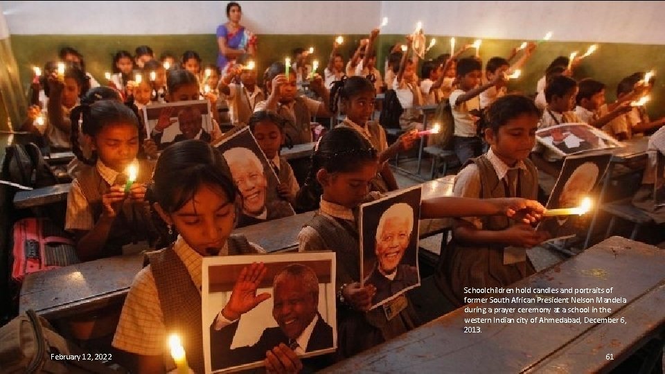 Schoolchildren hold candles and portraits of former South African President Nelson Mandela during a