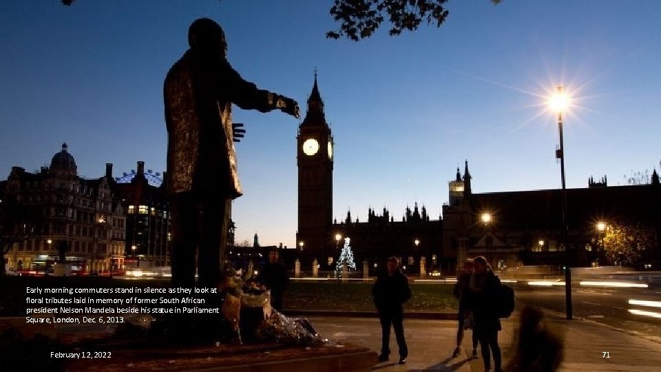 Early morning commuters stand in silence as they look at floral tributes laid in