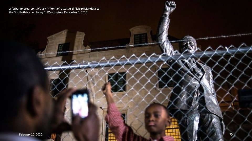 A father photographs his son in front of a statue of Nelson Mandela at