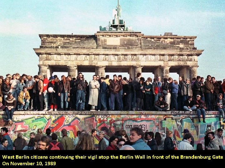 West Berlin citizens continuing their vigil atop the Berlin Wall in front of the