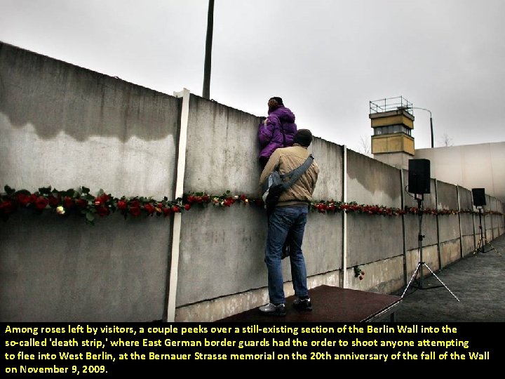 Among roses left by visitors, a couple peeks over a still-existing section of the