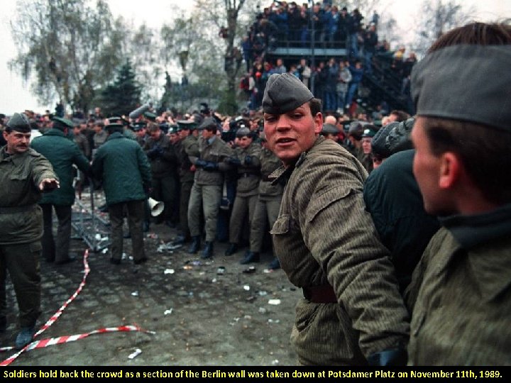 Soldiers hold back the crowd as a section of the Berlin wall was taken