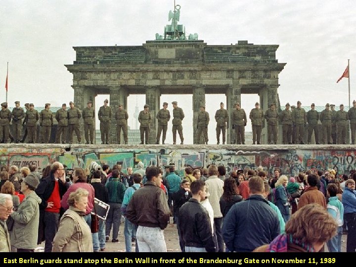 East Berlin guards stand atop the Berlin Wall in front of the Brandenburg Gate