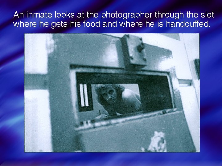 An inmate looks at the photographer through the slot where he gets his food