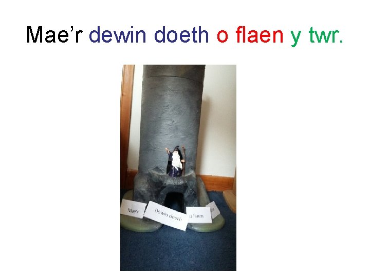 Mae’r dewin doeth o flaen y twr. 