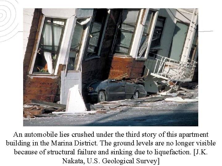 An automobile lies crushed under the third story of this apartment building in the
