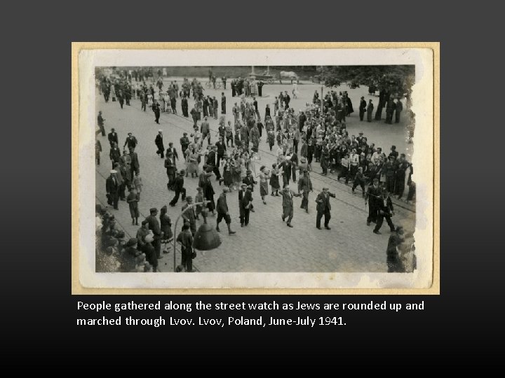 People gathered along the street watch as Jews are rounded up and marched through