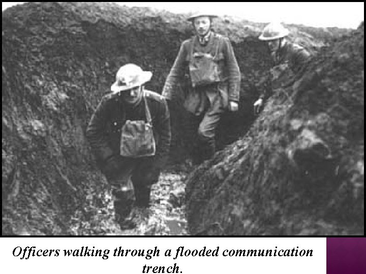 Officers walking through a flooded communication trench. 