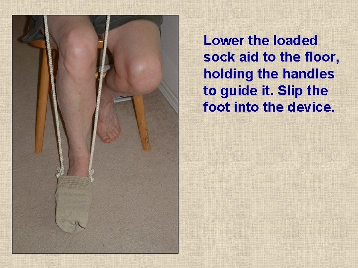 Lower the loaded sock aid to the floor, holding the handles to guide it. Lower the loaded sock aid to the floor, holding the handles to guide it.