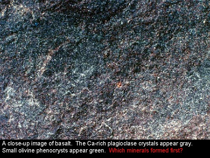 A close-up image of basalt. The Ca-rich plagioclase crystals appear gray. Small olivine phenocrysts