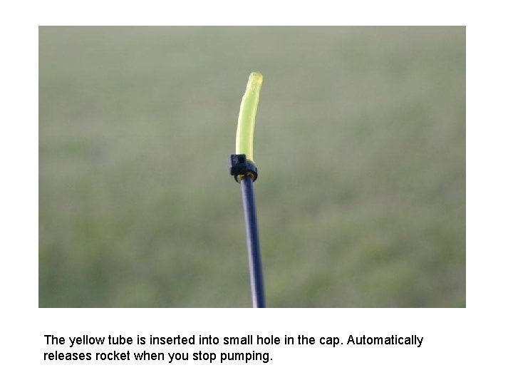 The yellow tube is inserted into small hole in the cap. Automatically releases rocket