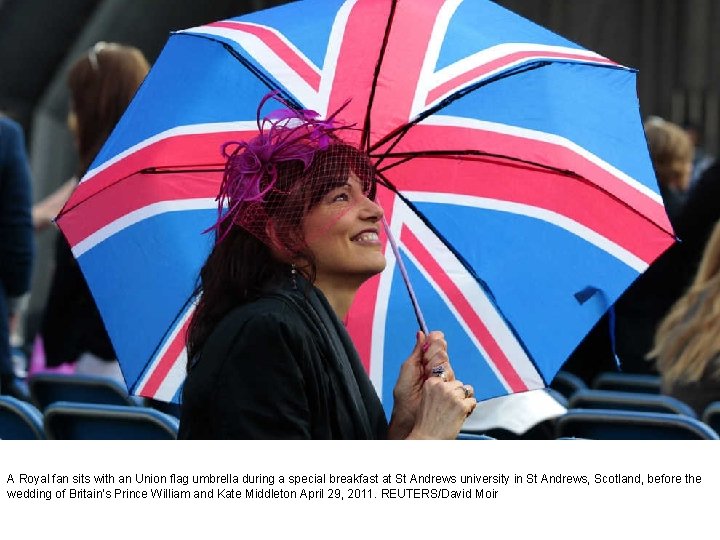 A Royal fan sits with an Union flag umbrella during a special breakfast at
