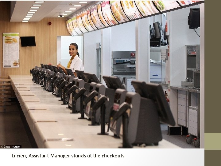 Lucien, Assistant Manager stands at the checkouts 
