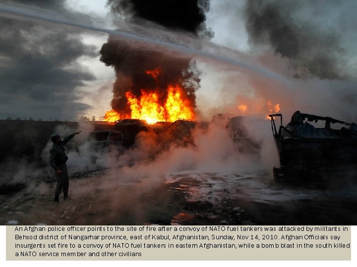 An Afghan police officer points to the site of fire after a convoy of