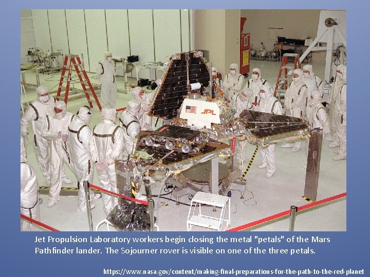 Jet Propulsion Laboratory workers begin closing the metal "petals" of the Mars Pathfinder lander.