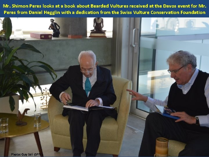 Mr. Shimon Peres looks at a book about Bearded Vultures received at the Davos