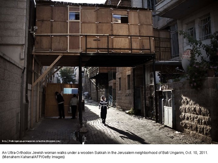 An Ultra-Orthodox Jewish woman walks under a wooden Sukkah in the Jerusalem neighborhood of