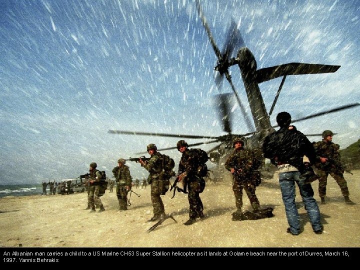 An Albanian man carries a child to a US Marine CH 53 Super Stallion