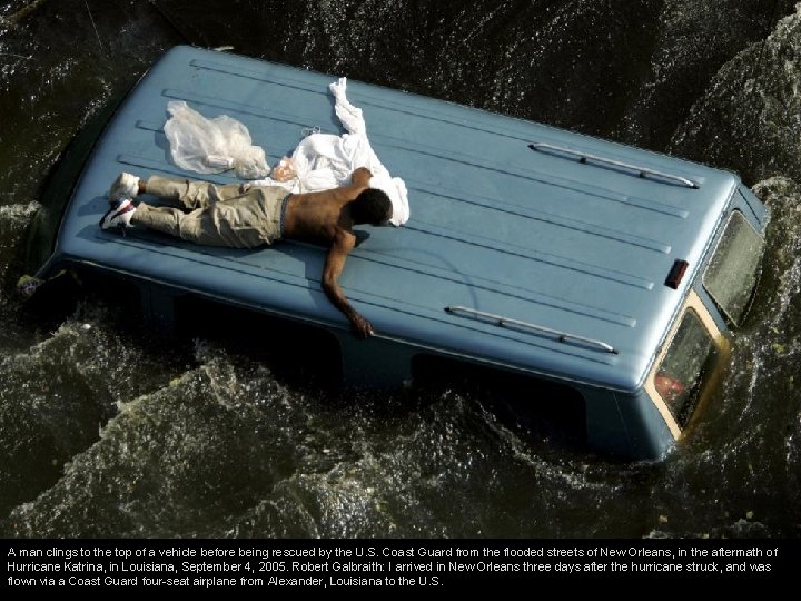 A man clings to the top of a vehicle before being rescued by the