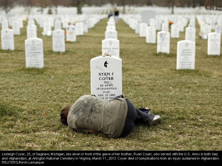 Lesleigh Coyer, 25, of Saginaw, Michigan, lies down in front of the grave of
