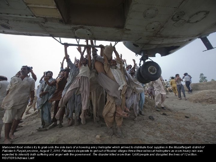 Marooned flood victims try to grab onto the side bars of a hovering army