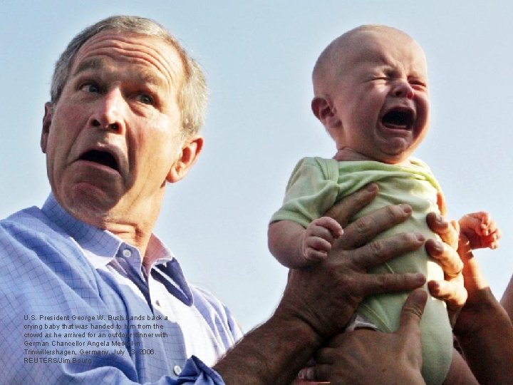U. S. President George W. Bush hands back a crying baby that was handed