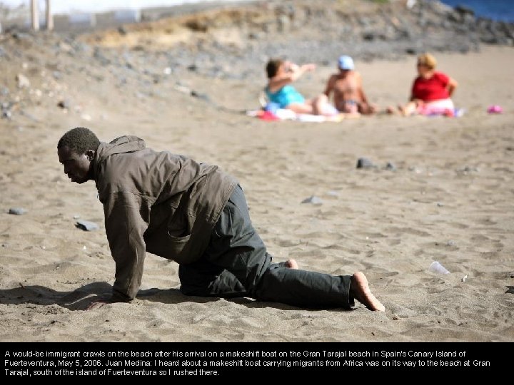 A would-be immigrant crawls on the beach after his arrival on a makeshift boat