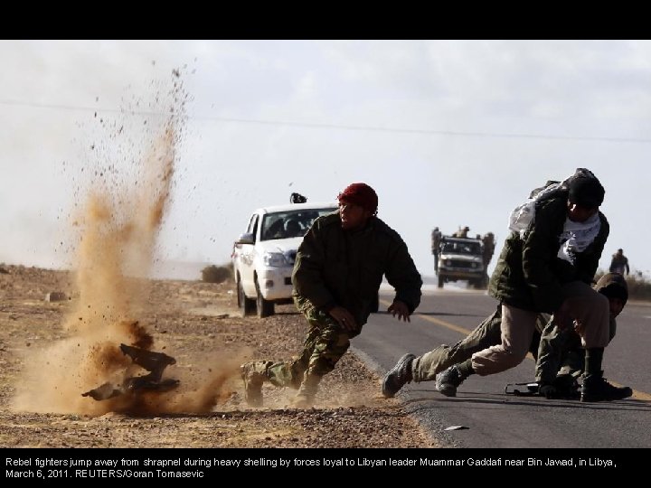 Rebel fighters jump away from shrapnel during heavy shelling by forces loyal to Libyan