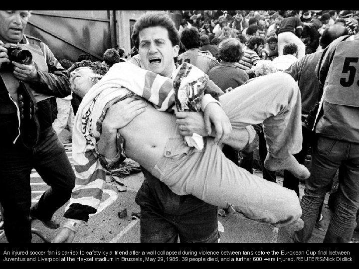 An injured soccer fan is carried to safety by a friend after a wall