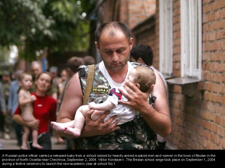 A Russian police officer carries a released baby from a school seized by heavily