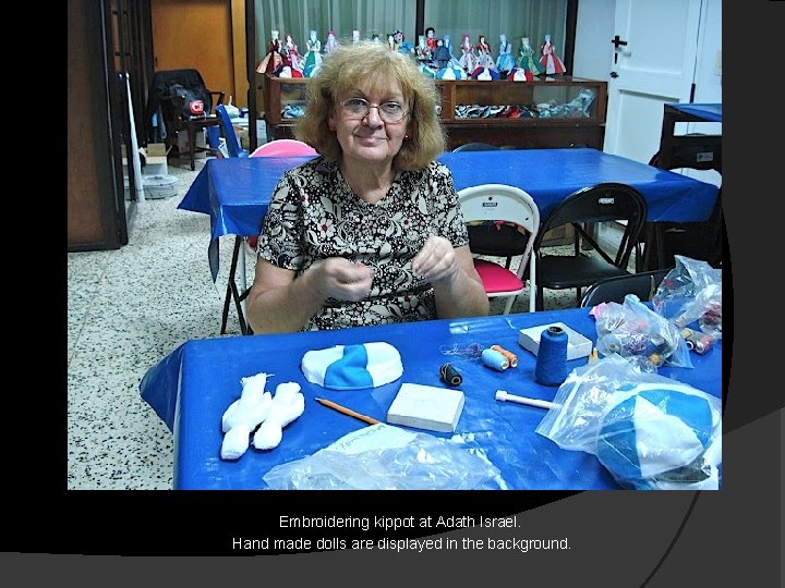 Embroidering kippot at Adath Israel. Hand made dolls are displayed in the background. 