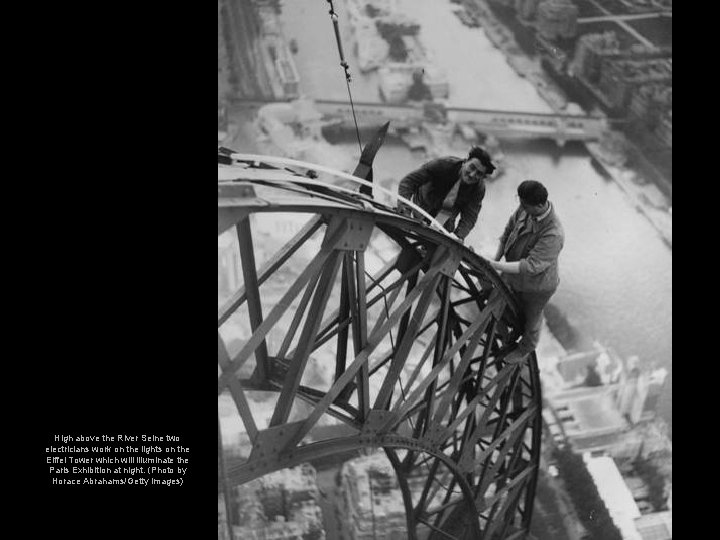 High above the River Seine two electricians work on the lights on the Eiffel