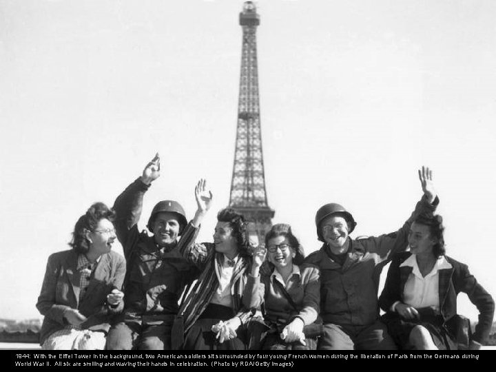 1944: With the Eiffel Tower in the background, two American soldiers sit surrounded by