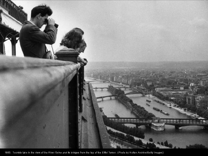 1950: Tourists take in the view of the River Seine and its bridges from