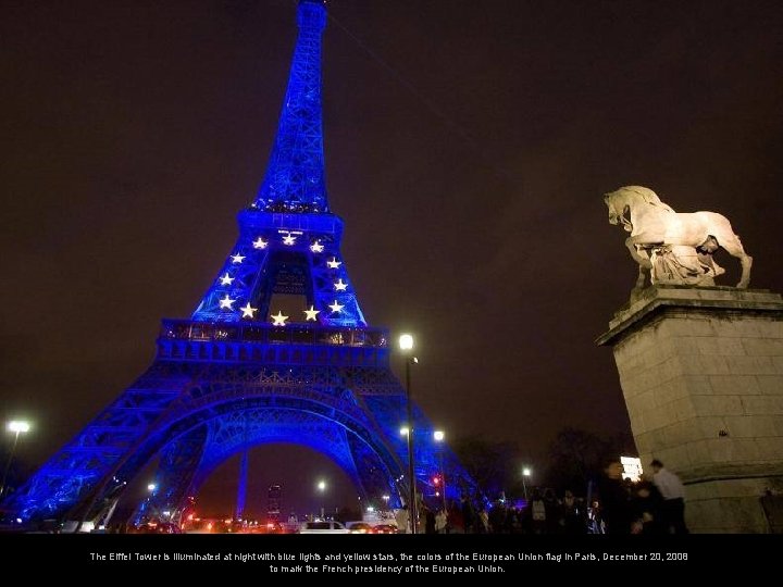 The Eiffel Tower is illuminated at night with blue lights and yellow stars, the