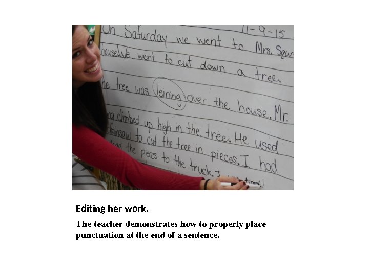 Editing her work. The teacher demonstrates how to properly place punctuation at the end