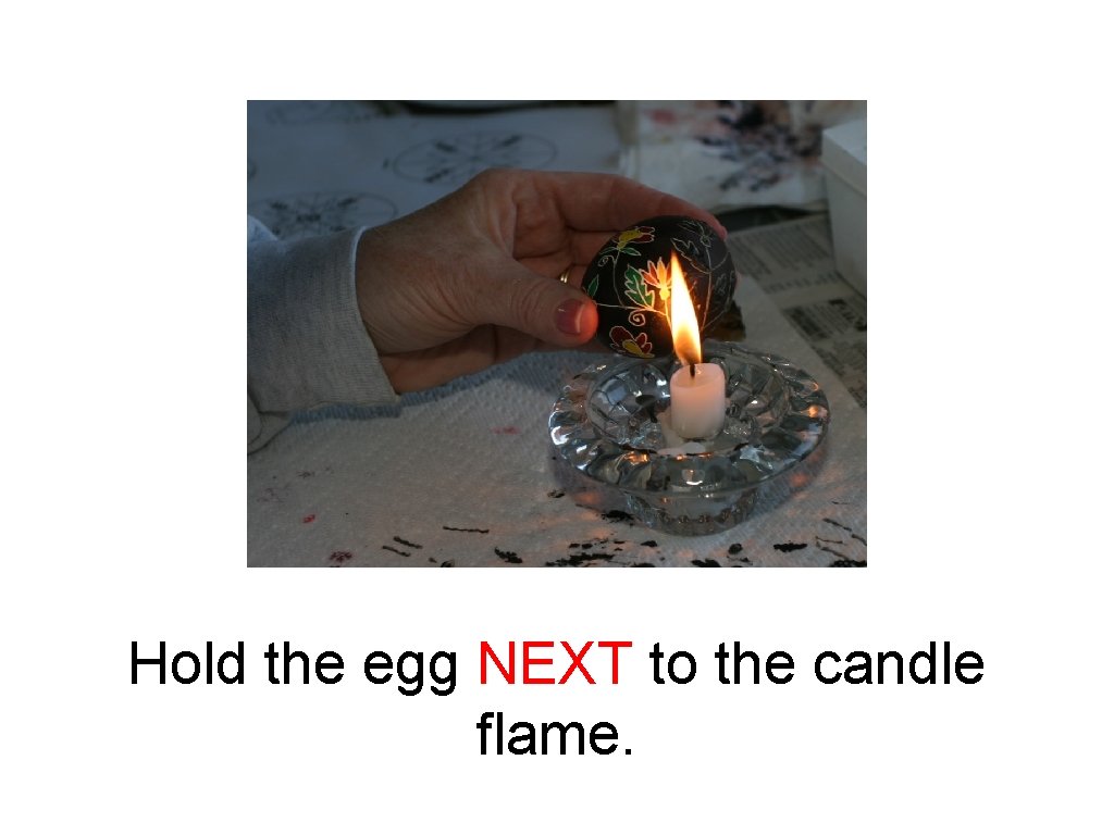 Hold the egg NEXT to the candle flame. 